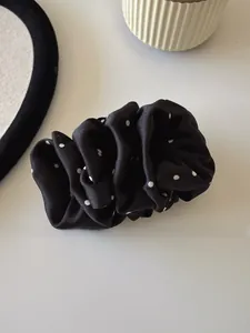 Detail of black polka dot scrunchie with silky satin pleats on a decorative tray