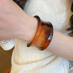 Detailed close-up of amber acrylic resin bangle on model with elegant warm tones