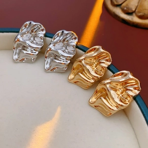 Close-up of irregular liquid-style gold and silver earrings with metallic texture