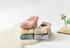 Close-up of cozy coral fleece socks with cute cartoon cat patterns on a plush white rug