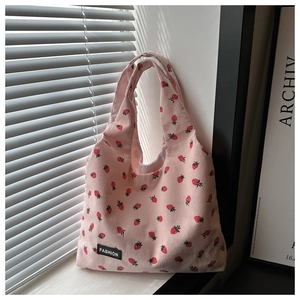 Detail of pink corduroy tote bag featuring red strawberry print and fashion label