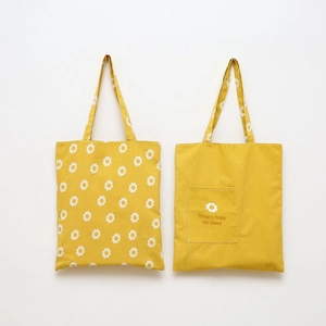 Detail of yellow canvas tote bag with daisy pattern and Flowers make me happy slogan