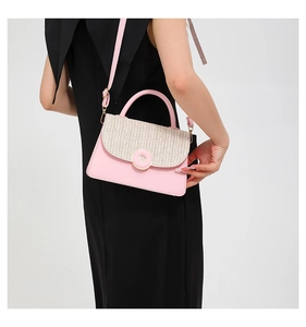 Pink PU leather and beige straw patchwork crossbody bag held by a model in a black dress