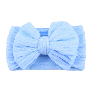Detail of light blue knitted nylon baby headband with large bow and cable stitch texture