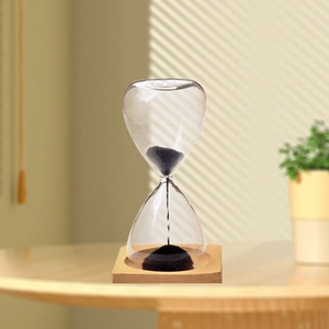Creative magnetic hourglass with black sand and square wooden base on desk