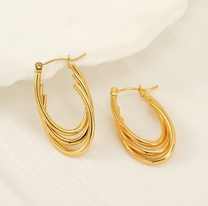 Detail of 18K gold layered triple line heart earrings on a textured backdrop
