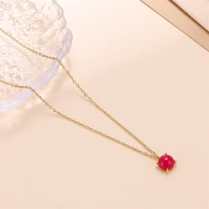 Macro shot of 18k gold necklace featuring a vibrant red natural stone pendant