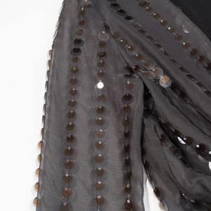 Detailed macro view of charcoal sequin embroidery on sheer dark grey chiffon fabric
