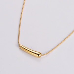 Macro detail of polished gold chili pendant on a minimalist snake chain necklace