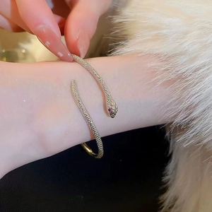 Zilveren slangenarmband met rode edelsteenogen op een witte bontachtergrond