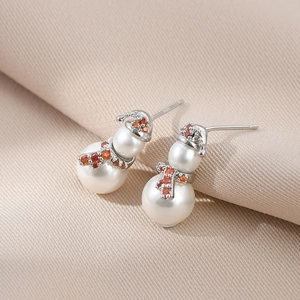 Macro view of S925 silver Christmas snowman earrings with white pearls and red zircons