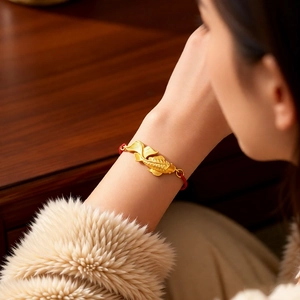 Detail of vintage golden koi fish pendant on a red braided bracelet with matte finish