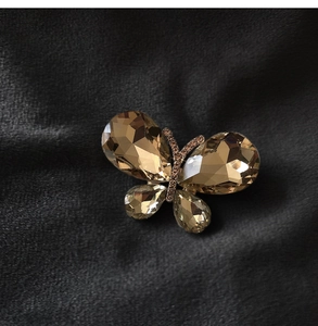 Macro shot of gold butterfly brooch with amber crystals on dark velvet fabric