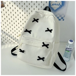 Detail view of white corduroy backpack with six black ribbon bows and side pockets