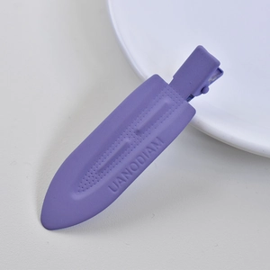 Close-up of a matte purple acetate hair clip with UANODIAM lettering on a white surface