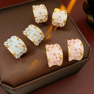 Détail de boucles d'oreilles fleurs plaquées or avec émail blanc, bleu et rose tendre