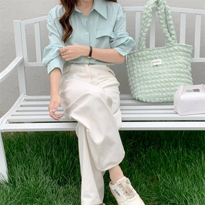 Outdoor shot of green bubble texture tote bag styled with casual white trousers and green shirt