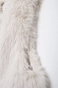 Close-up of fluffy off-white faux fur vest detailing the collar and soft shoulder texture