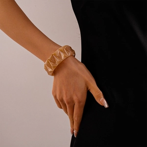 Close-up of amber acrylic cuff bracelet featuring 3D geometric textures on model wrist
