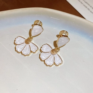 Gros plan de boucles d'oreilles fleurs élégantes avec base dorée et pétales émaillés