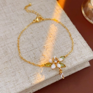 Dettaglio di un braccialetto di fiori smaltati placcato oro con zircone su lino