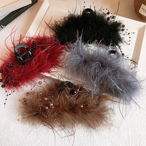 Detail showing plush feathers and beaded accents on colorful hair claws set on a tray