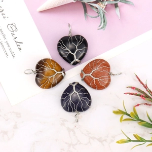Flat lay of four handmade wire wrapped heart shaped natural stone tree of life pendants