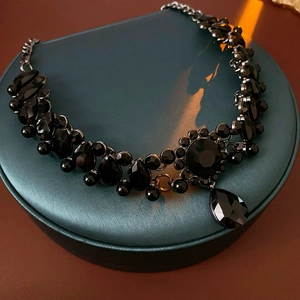 Detail of vintage necklace with black faceted stones and a teardrop pendant on a stand