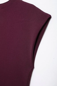 Detalle del vestido de punto rojo oscuro mostrando el corte de hombro y tejido