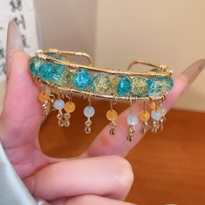 Détail de la manchette faite main en fil doré avec perles bleues et breloques suspendues