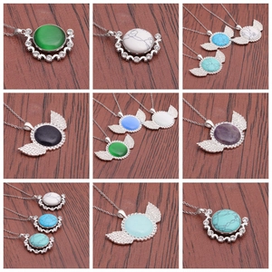 Macro view of crystal necklaces in moon and wing silver frames on a red wood base