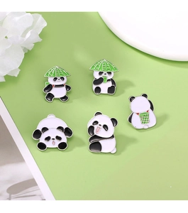 Close-up of five cute enamel panda pins with green bamboo hats on a decorative plate