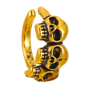 Detail of vintage gold skull ring with three motifs and black distressed finish