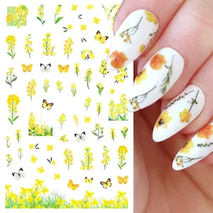 Close-up of yellow tulip and butterfly nail art stickers on milky white manicure