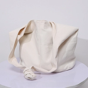 Detail of hobo shoulder bag with a decorative knotted strap on a minimalist canvas surface