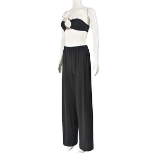 Détail d'un haut bandeau noir avec anneau en serpent métallique et pantalon large