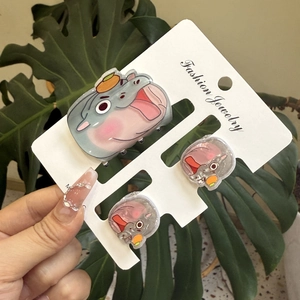 Detailed view of three cute acrylic hippo hair clips on a card held by hand