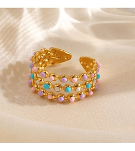Close-up of golden triple-layered ring with colorful enamel beads on beige satin fabric