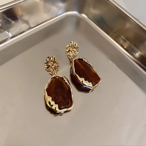 Detail of vintage geometric resin earrings with amber texture and gold irregular metal frames