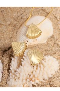 Close-up of golden shell jewelry set on white sand with coral and seashell accents