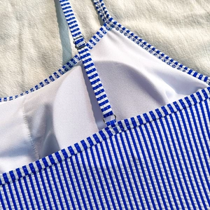 Detailed close-up of blue white striped swimwear with adjustable silver buckle