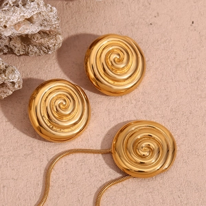 Macro detail of gold spiral shell pendant and earrings set on textured stone surface