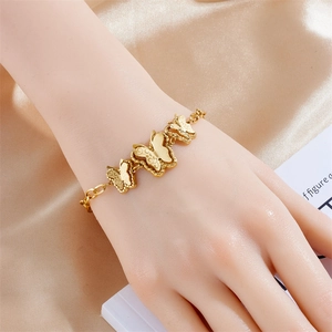 Elegant gold butterfly link bracelet with intricate filigree details on satin background
