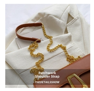 Detail of a brown leather shoulder bag featuring a gold chain strap and metal buckle