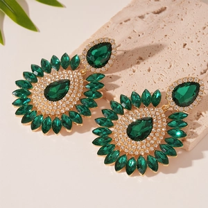 Detailed shot of green teardrop gems and rhinestones on gold vintage floral earrings