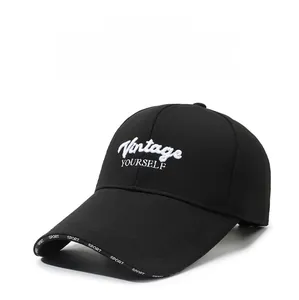Detail of white Vintage YOURSELF embroidery and SPORT print on a black baseball cap