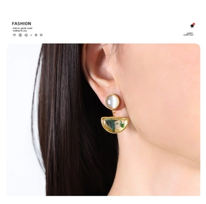 Detailed view of vintage cat-eye stone earrings with gold-rimmed green resin pendants