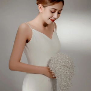 Elegant bridal bouquet featuring white pearls and flowers with a white V-neck wedding dress