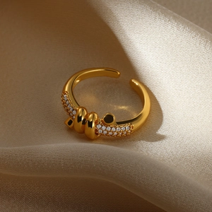 Detail of a minimalist gold heart zircon ring on a beige silk fabric background