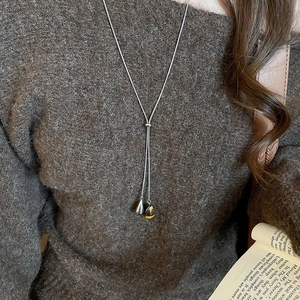 Close-up of silver snake chain necklace with double teardrop pendants on brown sweater
